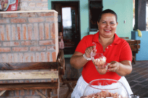 Para garantizar la sostenibilidad del proyecto, los propietarios y propietarias de los comedores y locales han conformado la Asociación de Desarrollo Comunal (ADESCO), para unir sus esfuerzos y dirigirse ante las entidades públicas y otras fuentes de financiamiento para cubrir las necesidades comunales. Nova, en la foto, es la presidenta y propietaria de uno de los nuevos comedores. A sus 50 años, sustituyó su humilde ramada por un nuevo comedor. 